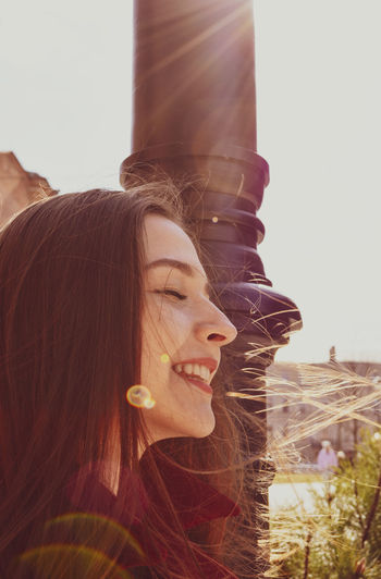 Close-up portrait of smiling young woman against sky