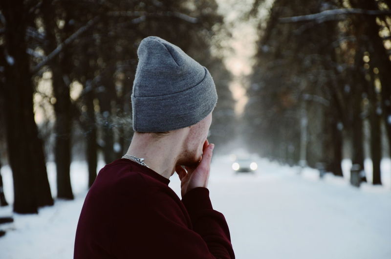 Side view of man wearing warm clothing on snow covered land during winter