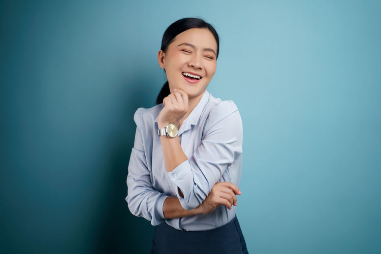 Smiling young woman against blue background