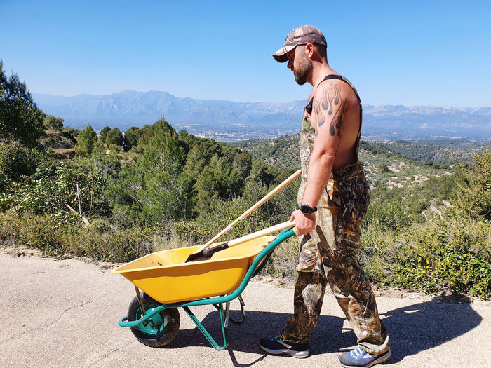 Tattooed man holding wheelbarrow