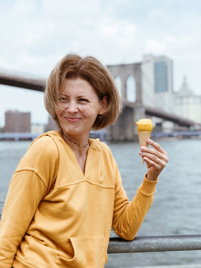 Tourist beautiful woman eats a cone of sorbet against the background of manhattan.