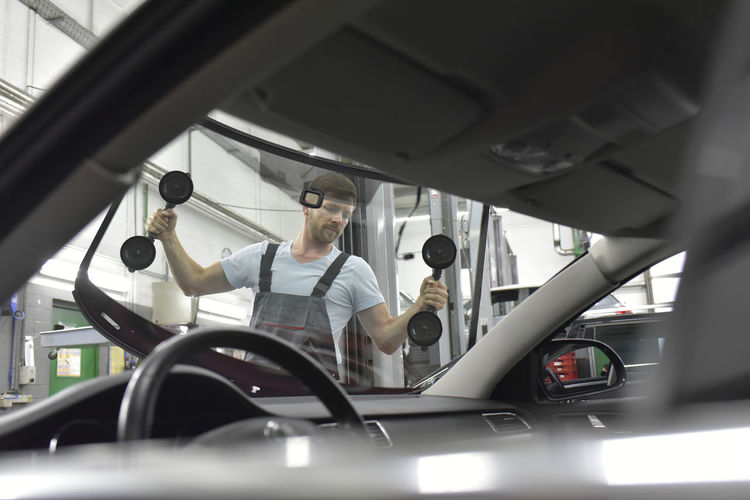 Car mechanic in a workshop changing car window