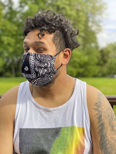 Portrait of young man wearing mask winking at park