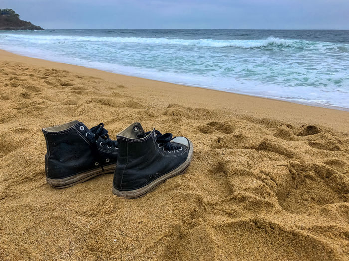 High angle view of shoes on sand at beach against sky