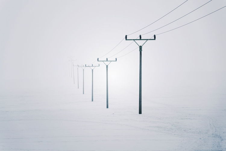 Electricity pylons from distribution power station disappearing in deep fog