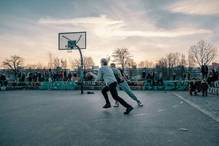 People playing basketball court against sky during winter