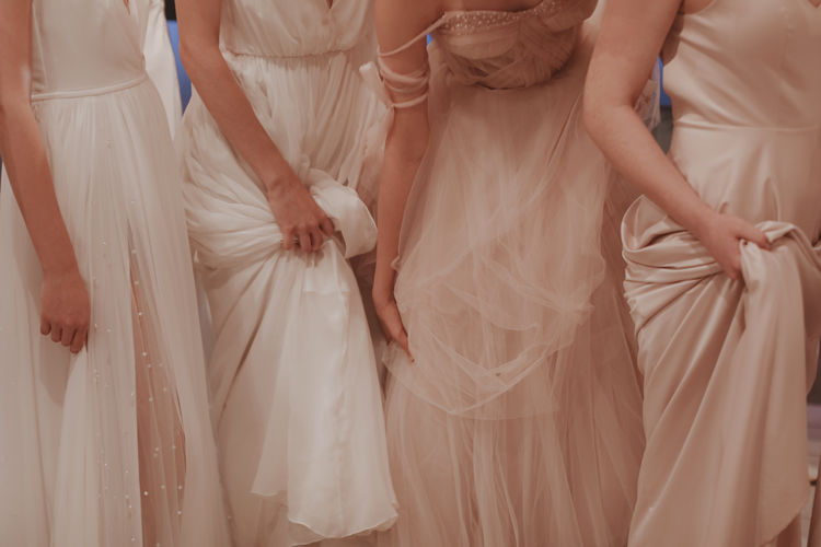 Cropped figure of women holding the hem of a long dress. wedding fashion