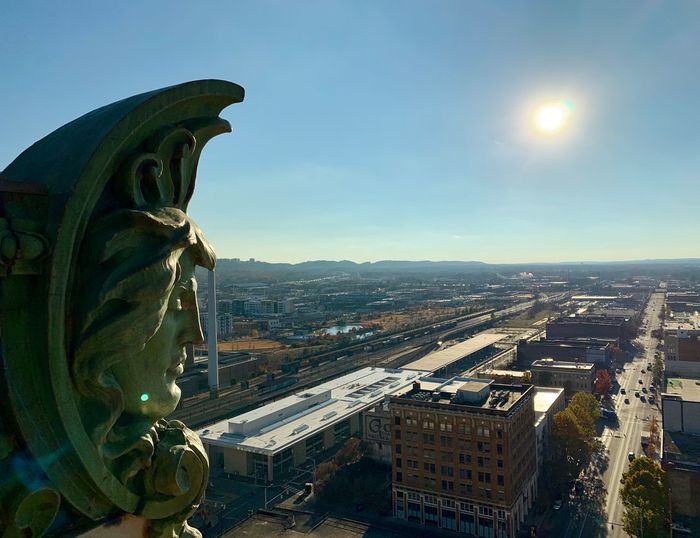 Statue amidst buildings in city against sky