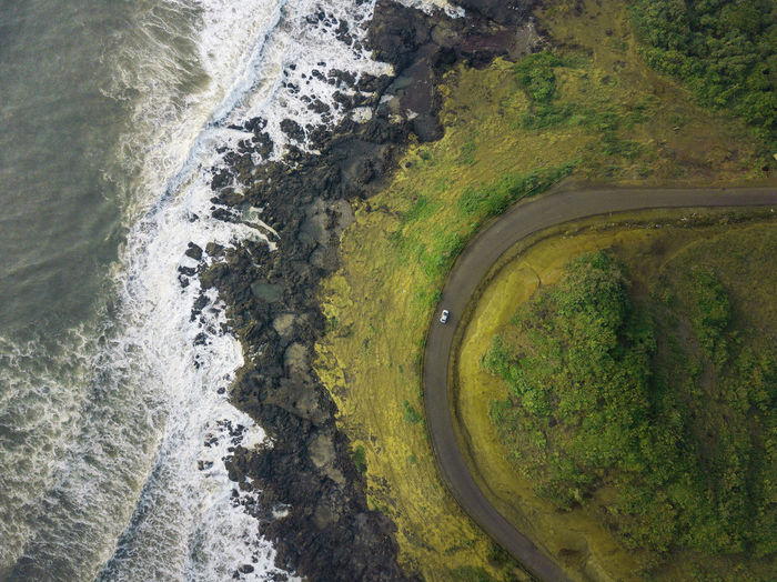 Aerial view of road by sea amidst field