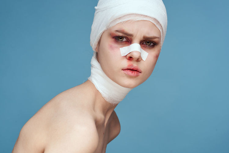 Young woman wearing bandage against colored background