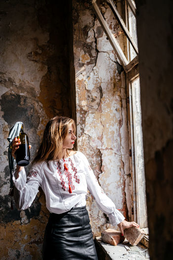 Side view of woman standing in abandoned house
