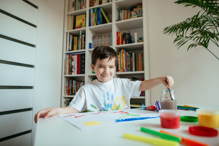 Portrait of boy doing painting while sitting at home