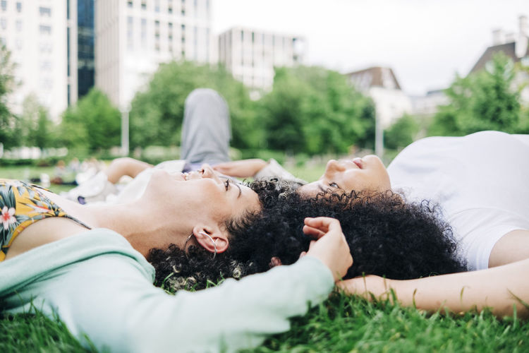 Male and female friends lying on grass at park