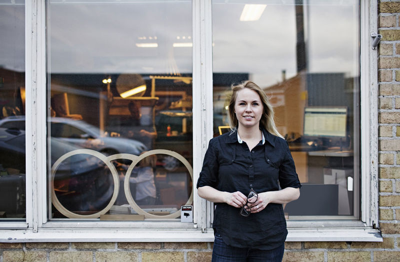 Portrait of confident female owner standing outside eyeglasses workshop