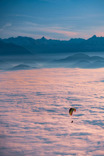 Silhouette of person paragliding over cloudscape