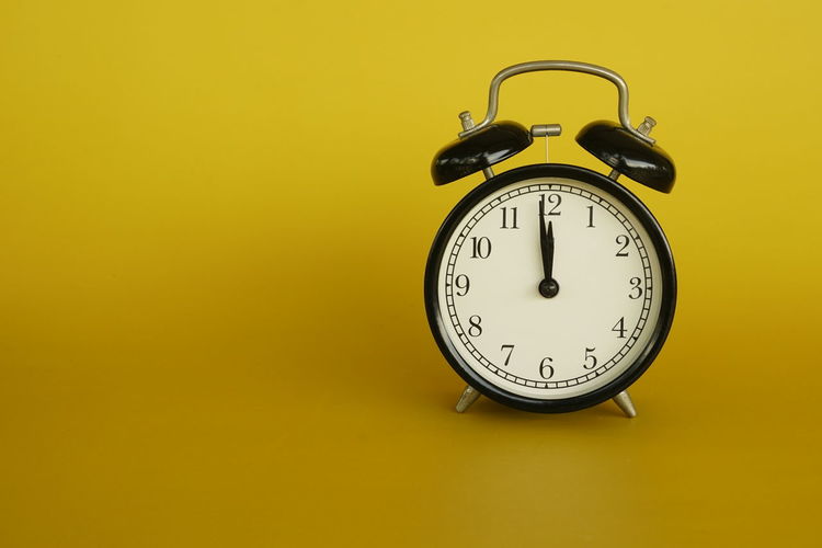 Close-up of clock on yellow background