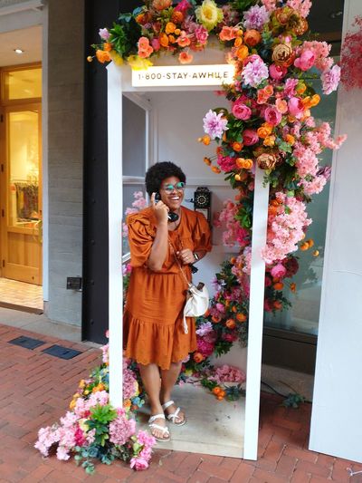 Woman standing in phone booth with flowers