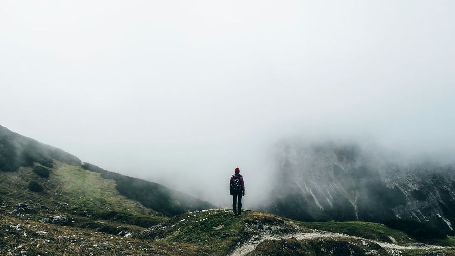 Rear view of woman standing on mountain during foggy weather