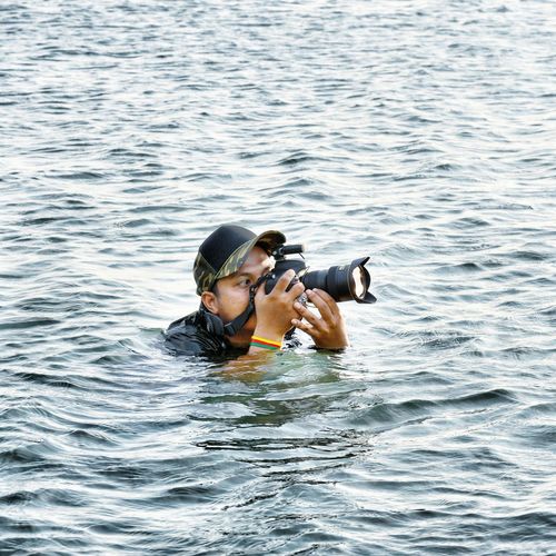 Man photographing with camera in sea