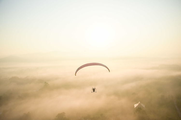 Person paragliding against sky during sunset