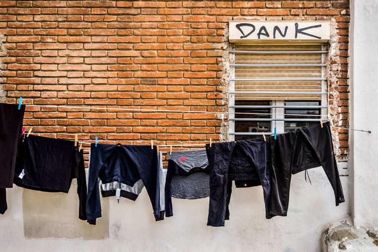 Row of clothes hanging against brick wall