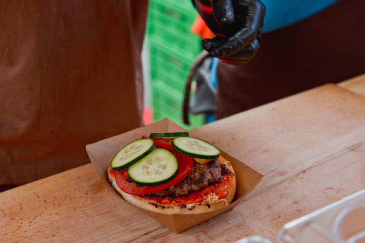 Cropped image of vendor preparing hamburger on table at market