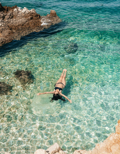Woman floating on water on beautiful beach with turquoise water on pag island in croatia.
