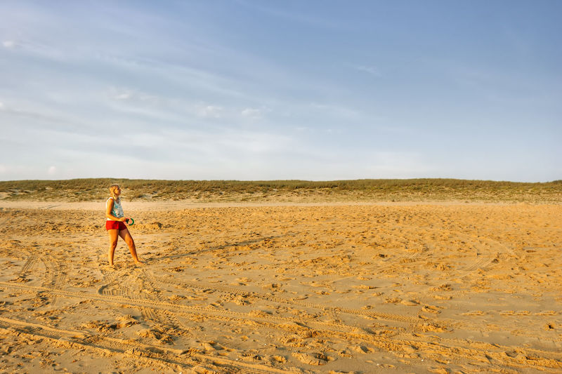 Full length of woman standing on sand against sky