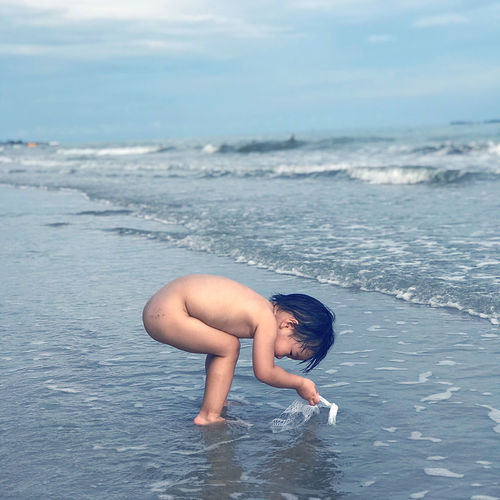 Full length of shirtless boy in sea