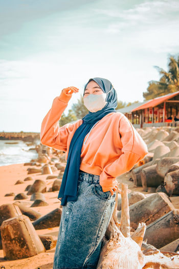 Woman standing at beach against sky