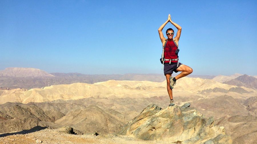 Full length of man doing yoga on landscape against sky