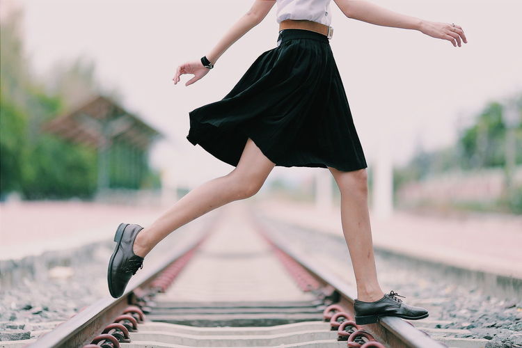Low section of woman crossing railroad track