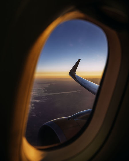Airplane wing seen through window during sunset