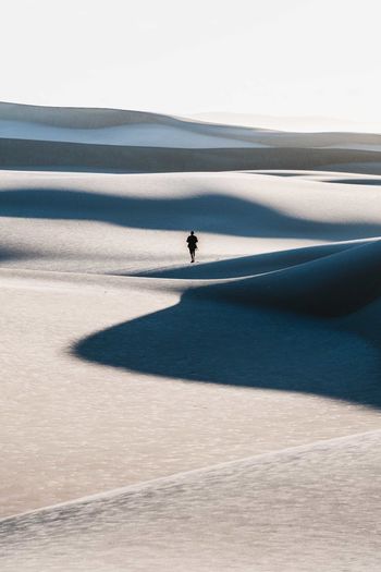 Mid distance view of man walking on sand dune