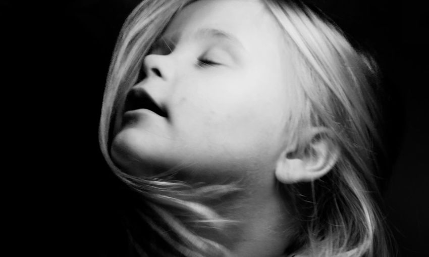 Close-up of girl with eyes closed against black background