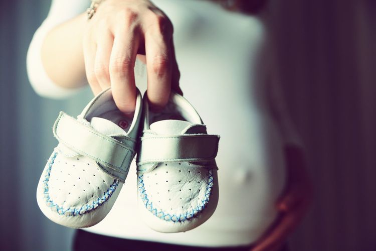 Pregnant women showing baby booties in hand