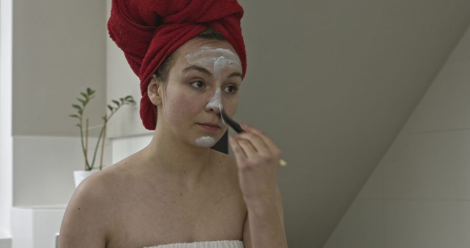 Woman applying facial mask at bathroom