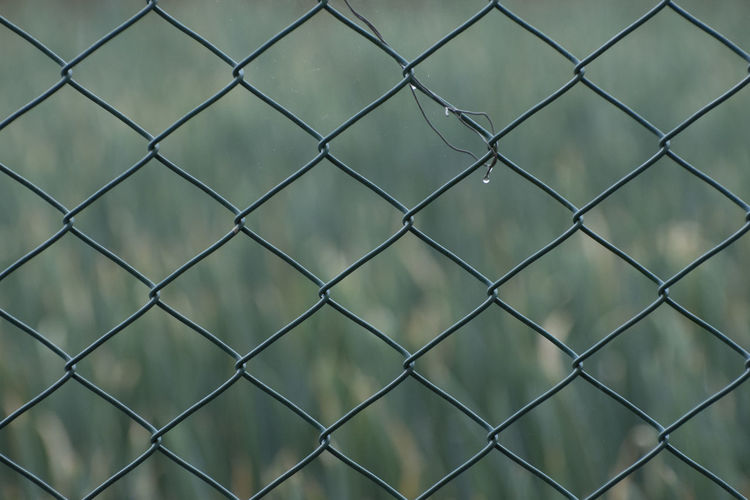 Full frame shot of chainlink fence against wall