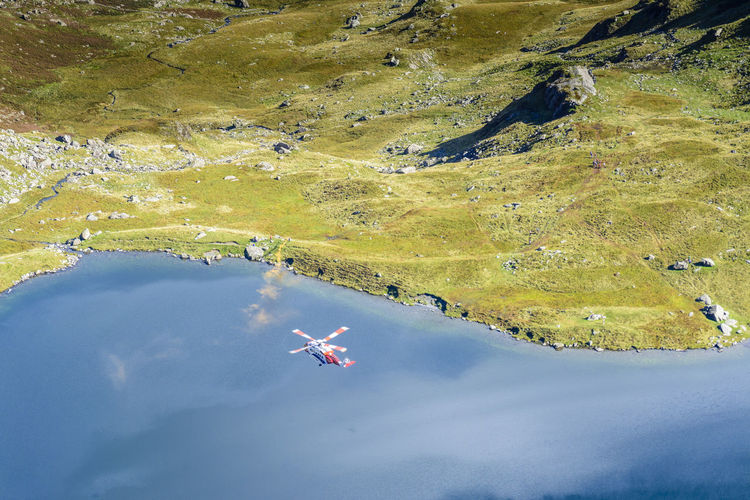 Aerial view of rescue helicopter flying over lake at snowdonia national park