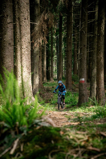 Young woman riding a mountain bike on footpath in the forest. salzburg, austria.