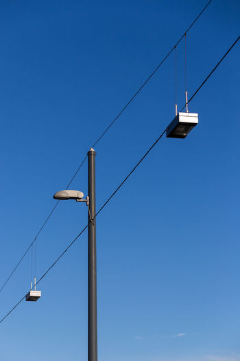 Low angle view of street lights against blue sky