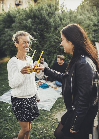 Happy female friends toasting elderflower drinks at rooftop party