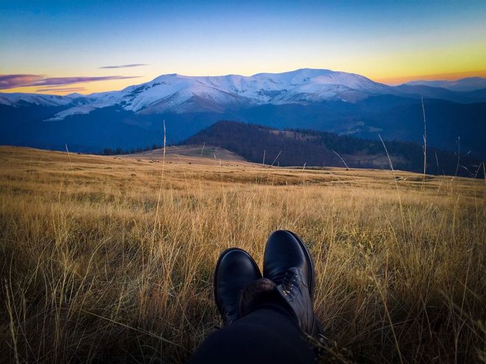 Black boots and snowcapped mountains in the background at sunset