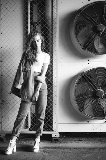 Portrait of teenage girl standing against exhaust fans