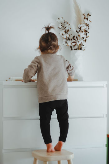 A child small girl stands backwards near white commode