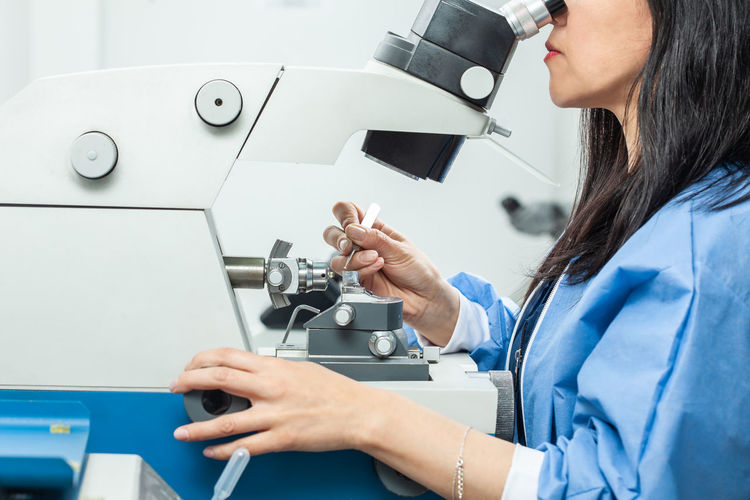 Female scientist placing a sample on a transmission electron microscopy grid