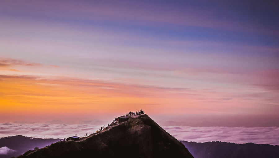 Silhouette building on mountain against sky during sunset