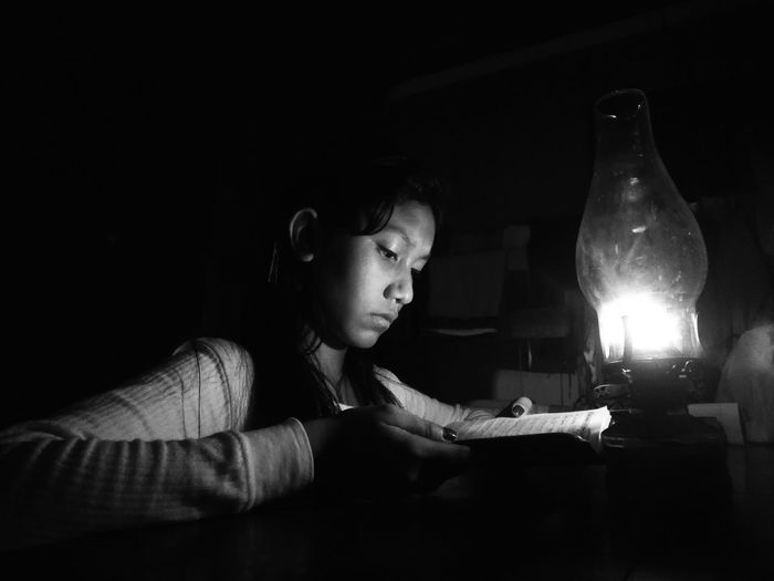 Teenage girl reading book in darkroom