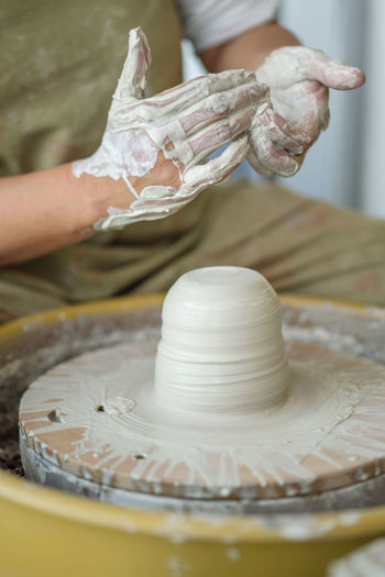 Midsection of woman making pottery in workshop