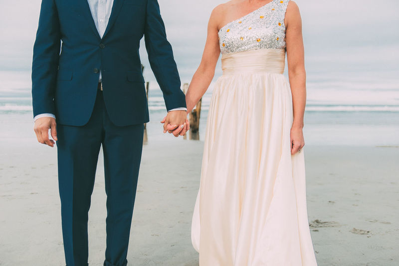 Newlyweds holding hands beach wedding